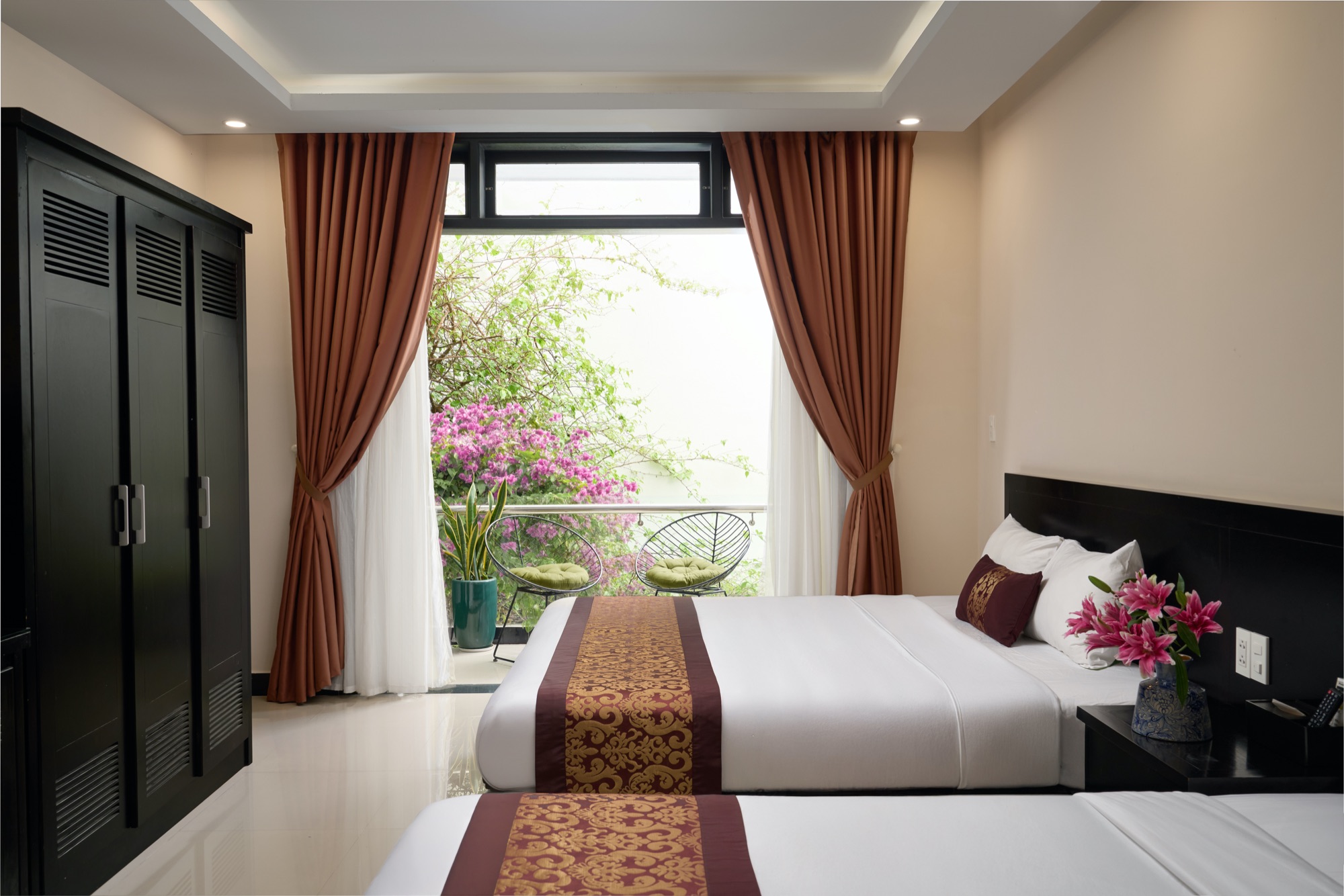 A room with curtains open to a balcony framed by bougainvillea