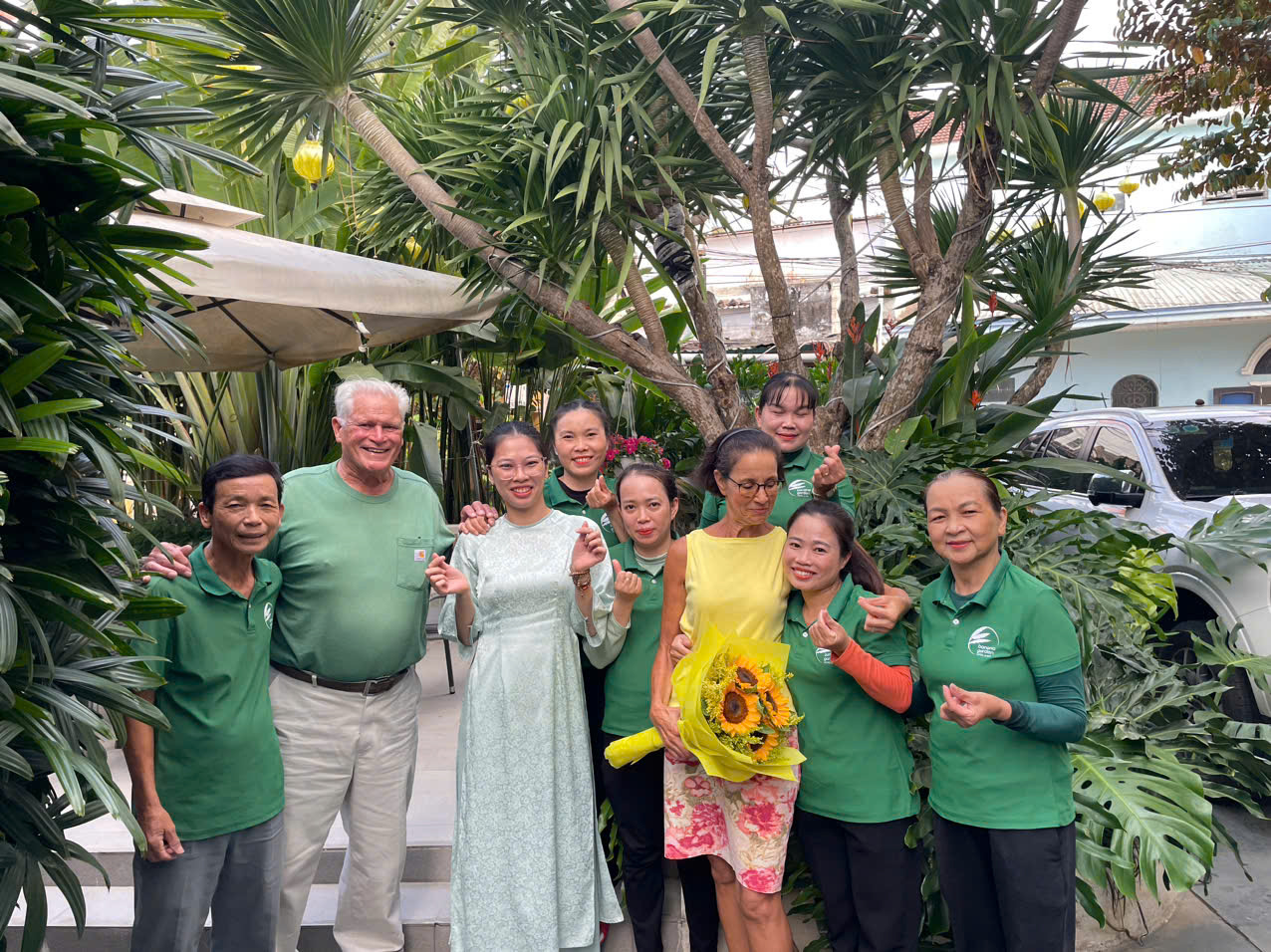 Guests and staff posing with a sunflower bouquet in the garden