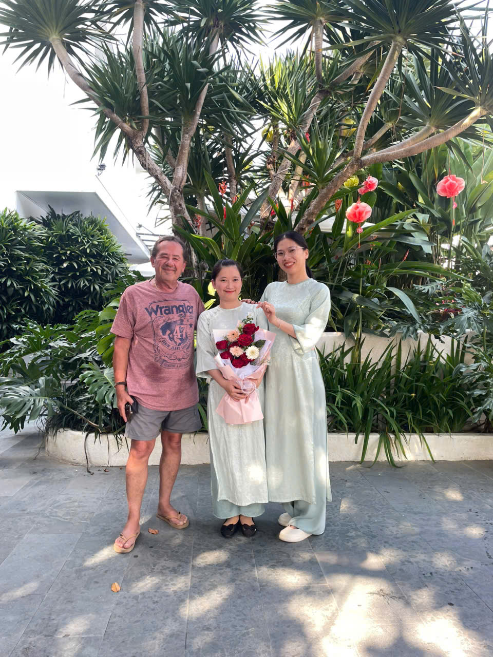 A guest holding a rose bouquet with staff in the garden
